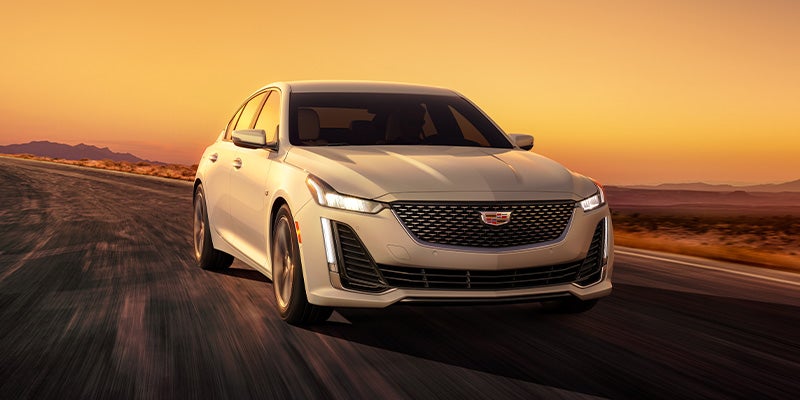 White Cadillac CT5-v driving on a desert highway at sunset