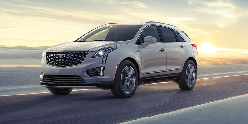 silver 2024 cadillac xt5 driving down a sunny road