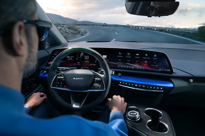 Front View of the 2026 OPTIQ-V Driving Through the Dusk Utilizing its Headlights | Brown & Wood Cadillac in Greenville NC