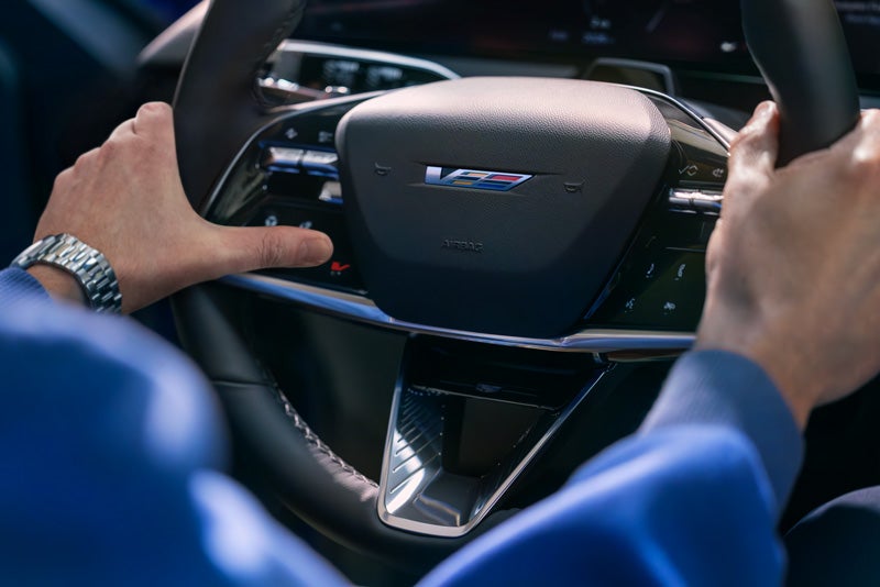 Close-up of a Man About to Press the V-Button on the 2026 OPTIQ-V Steering Wheel | Brown & Wood Cadillac in Greenville NC