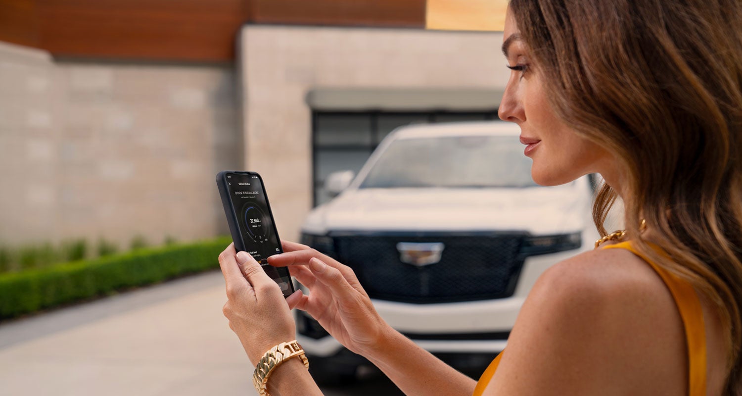 lady checking her mobile with a Cadillac vehicle background | Brown & Wood Cadillac in Greenville NC